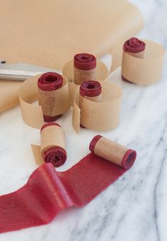 several rolls of red tape sitting on top of a table next to scissors and paper