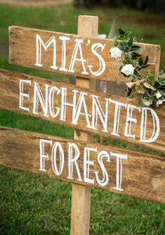 a wooden sign that says mia's enchanted forest and flowers on it