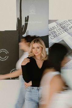 a woman standing in front of a wall with posters on it