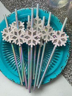 several snowflakes are sitting on a blue plate with silver straws in it