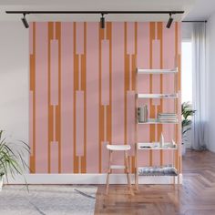 an orange and pink striped wallpaper in a living room with wooden flooring, bookshelf and plant