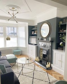 a living room filled with furniture and a fire place under a mirror on the wall