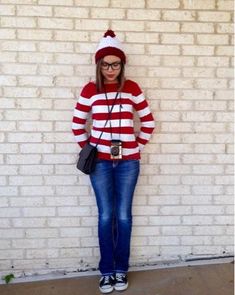 a woman standing in front of a brick wall wearing a red and white striped sweater