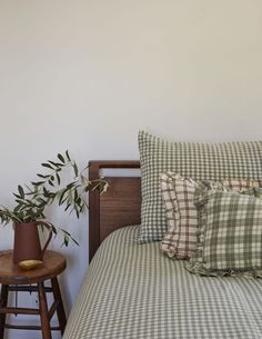 a bed with green and white checkered comforter next to a wooden side table