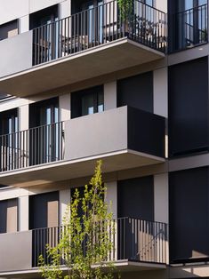 an apartment building with balconies and trees in the foreground