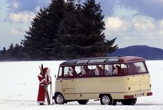 an old bus is parked in the snow with people dressed as santa claus and reindeer