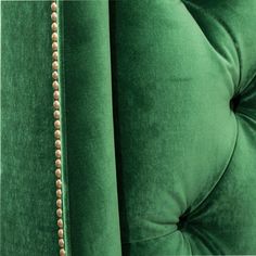 the back of a green velvet couch with buttons on it's arms and legs