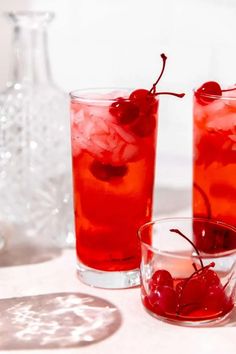 two glasses filled with red liquid and cherries