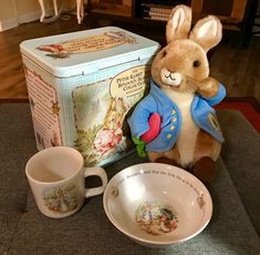 a stuffed rabbit sitting next to a cup and saucer