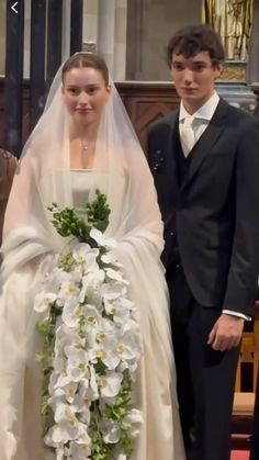 a young man and woman standing next to each other in front of a church alter