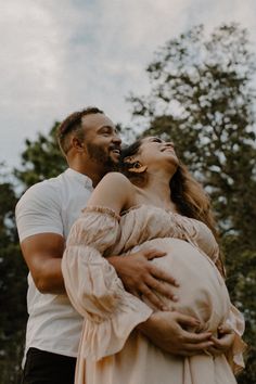 a man and woman standing next to each other with trees in the back ground behind them