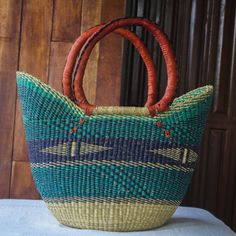 Presented by Ghana's Adams Salley this pretty shopping basket is hand crafted from raffia fibers in natural jade and cobalt. The basket features leather-wrapped handles for comfort and added durability. Use it as a handy shopping companion or display it in your home as a unique African decor accent. The Ewe word Nutifafa means peace be unto you . Blue Handwoven Jute Straw Bag, Green Woven Basket Straw Bag, Blue Woven Basket Straw Bag, Eco-friendly Blue Handwoven Straw Bag, Blue Basket Straw Bag For Travel, Blue Straw Shopping Bag, Green Handwoven Basket Straw Bag, Blue Handwoven Bucket Straw Bag, Blue Handwoven Straw Bucket Bag