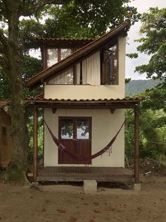 a small house with a hammock hanging from it's roof and windows