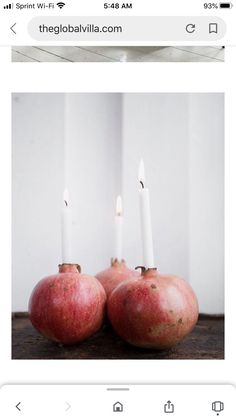 two pomegranates with candles in them sitting on top of a table