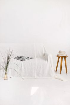 a white room with a small table, chair and blanket on the floor next to it