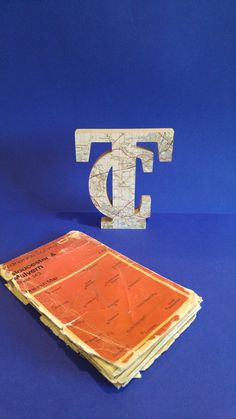 the letter d is made out of wood and sits next to a stack of old envelopes