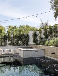 an outdoor hot tub in the middle of a patio with string lights hanging above it