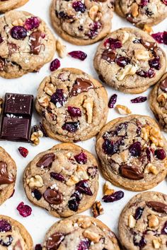 chocolate chip cookies with cranberries and walnuts on a white tablecloth next to a bar of milk