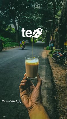 a hand holding up a drink with the word tea on it