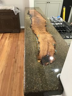 a kitchen counter with a large piece of wood on it's side and a stove top in the background