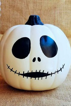 a white pumpkin decorated with black eyes and a jack - o'- lantern face