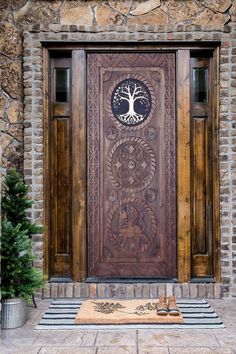 a wooden door with a tree on the front and side panel, surrounded by stone walls