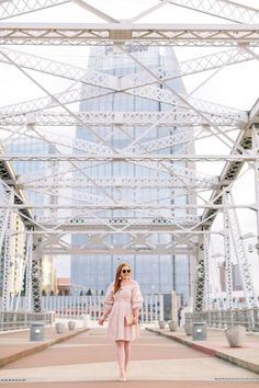 a woman in a pink dress standing under a bridge