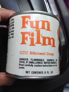 a person holding a can of orange flavored film