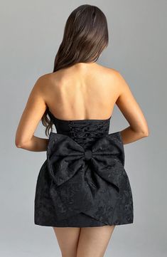 THE dress of the season has landed and you're going to be obsessed. Meet Elenora, our dreamy mini with a pretty structured skirt and waist cinching bodice. This strapless style is complete with lace up and an oversized bow to the back for perfect feminine drama. 



Colour: Black.

Premium non-stretch floral jacquard.

Strapless design.

Waist cinching.

Detachable bow.

Oversized bow detail to back.

Voluminous, structured skirt.

Lace up to the reverse.

Mini length.

Model is an XS and is wea Homecoming Dresses Corset, Structured Skirt, Tied Dress, Midi Dress Wedding Guest, Satin Homecoming Dress, Maxi Dress Sale, Sparkle Dress, Dresses Ideas, Floral Jacquard