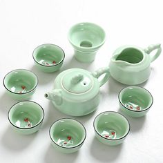 a tea set with cups and saucers on a white table top next to each other