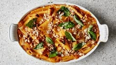 a casserole dish filled with pasta, spinach and cheese on a table