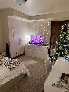 a bedroom with a christmas tree in the corner and a tv on top of it