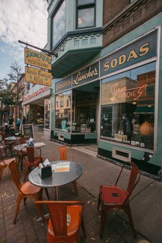 tables and chairs are outside in front of a soda shop on the side of the street