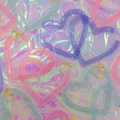 many different colored hearts on a pink and blue holographic background with gold hoop earrings