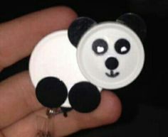 a person holding a panda bear button in their hand