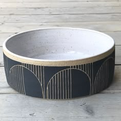 a black and white bowl sitting on top of a wooden table