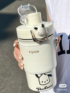 a person holding a white water bottle with a cow on it's side and the lid open