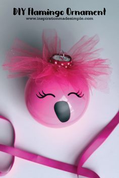 a pink flamingo ornament with a candle on it and a pink ribbon