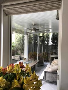 an outdoor living area with couches, tables and flowers in vases on the table