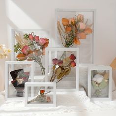 four frames with flowers in them sitting on a bed