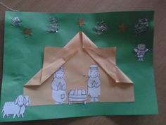 an origami christmas scene made out of paper on a green sheet of paper