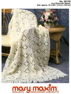 a white crocheted blanket sitting on top of a chair next to a table