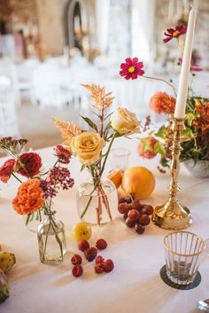 the table is set with flowers, fruit and candlesticks for an elegant wedding reception