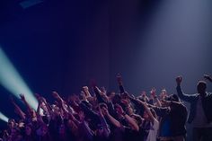 a group of people standing on top of a stage with their hands in the air