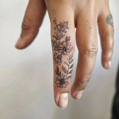 a person's hand with a flower tattoo on the middle finger and an arrow in the middle