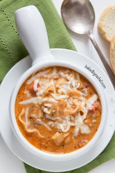 a white bowl filled with soup next to two slices of bread on top of a green napkin