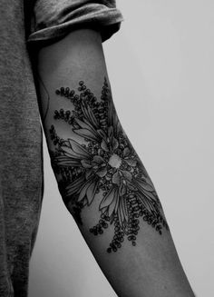 a black and white photo of a person's arm with flowers on the wrist