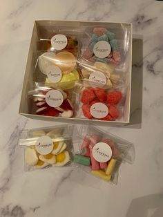 two boxes filled with different types of candies on top of a marble countertop