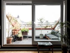 a living room with an open sliding glass door and potted plants on the windowsill