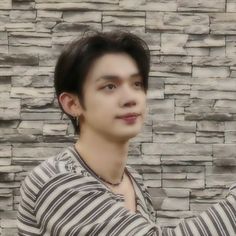 a young man is taking a selfie in front of a stone wall with his cell phone